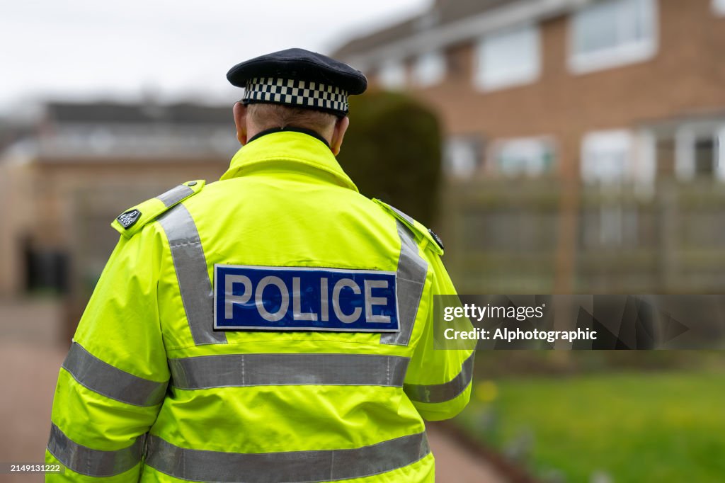 A policeman walking away from an elderly person's home.