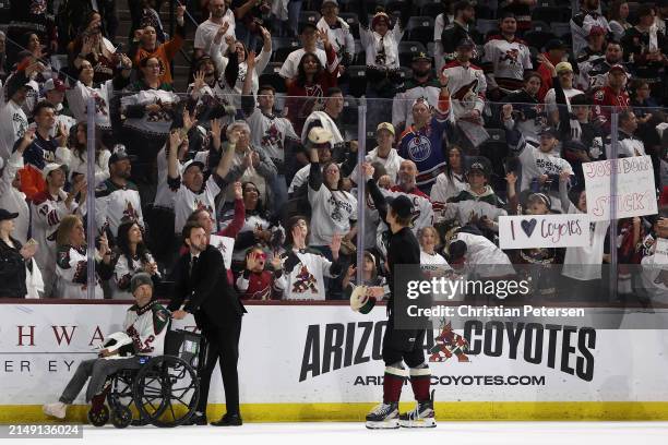 Josh Doan of the Arizona Coyotes throws hats for fans following the NHL game against the Edmonton Oilers at Mullett Arena on April 17, 2024 in Tempe,...