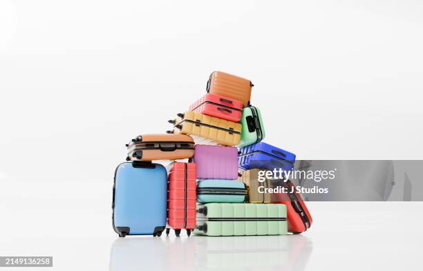 large pile of colourful luggage on a white background - plein photos et images de collection