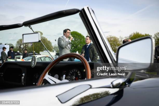 LONDON, ENGLAND Guests enjoy a glass of champagne as they stand next to a 1965 Jaguar E-type Series 1 4.2l Roadster on the press day of the Salon...