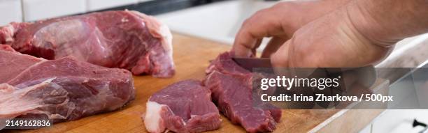 midsection of man cutting meat on board - carnicero fotografías e imágenes de stock