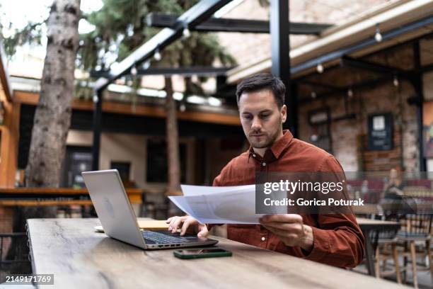photo of a young man working at coffee shop using modern technologies - freelance work stock pictures, royalty-free photos & images
