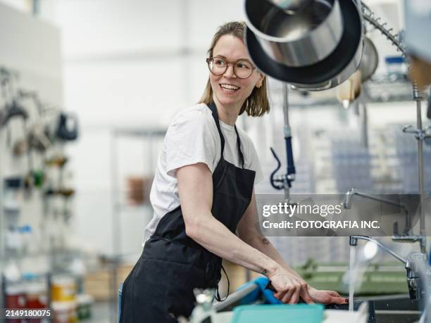 eine chocolatierin bei der arbeit in der schokoladenfabrik - geschirr spülen stock-fotos und bilder