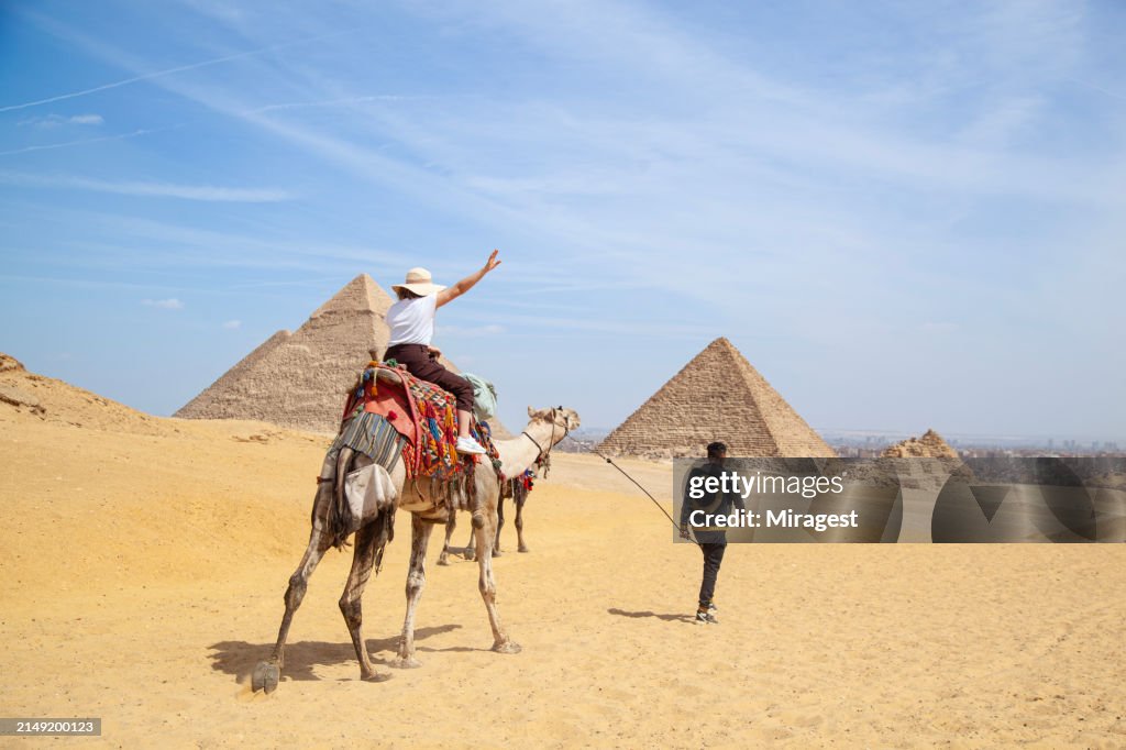 Turista andando de camelo no deserto egípcio e visita as pirâmides no Cairo.