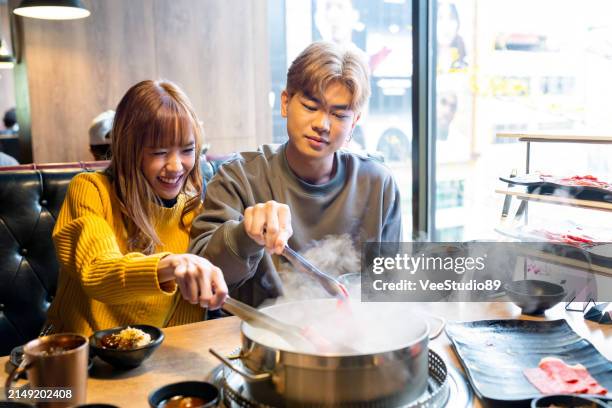asian couple having lunch eating hot pot together at restaurant - steamboat stock pictures, royalty-free photos & images