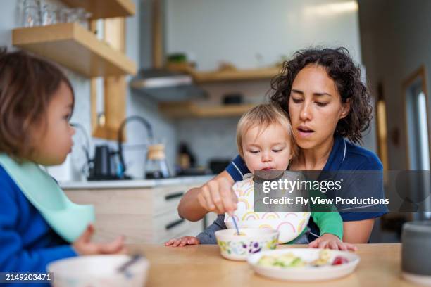 eurasian mom feeding toddler son breakfast - feeding stock pictures, royalty-free photos & images