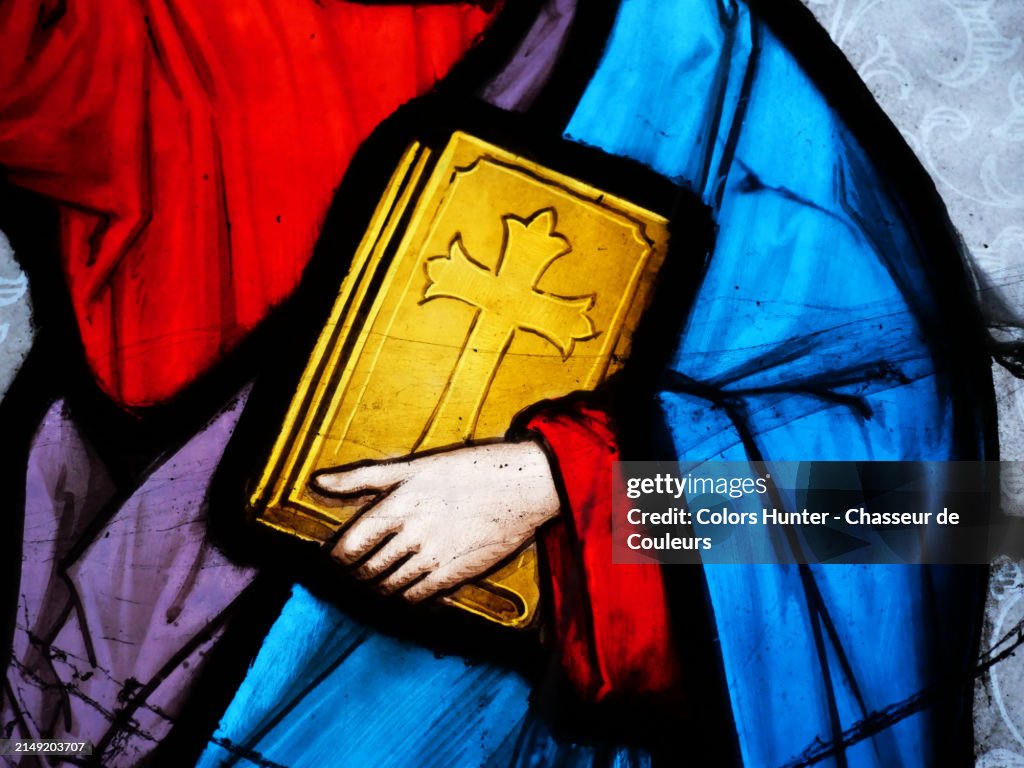 A hand holds the bible against the toga of a religious person.
Close-up of a colorful stained glass window backlit by the sun. Natural colors.
Photograph taken in an abandoned funeral chapel at the Pere Lachaise cemetery in Paris, France.