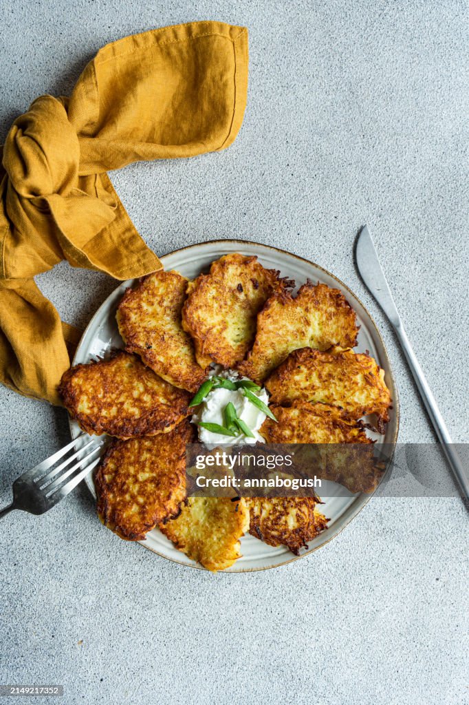 Overhead view of a Plate of fried potato pancakes with sour cream, spring onion and dill