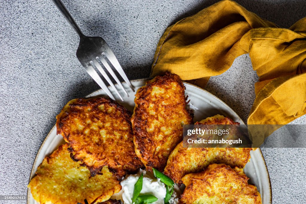 Overhead view of a Plate of fried potato pancakes with sour cream, spring onion and dill