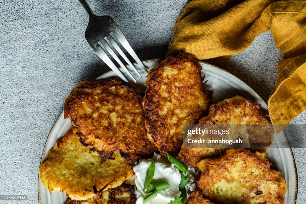 Overhead view of a Plate of fried potato pancakes with sour cream, spring onion and dill