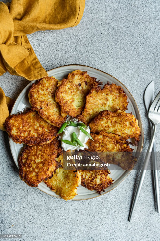 Overhead view of a Plate of fried potato pancakes with sour cream, spring onion and dill