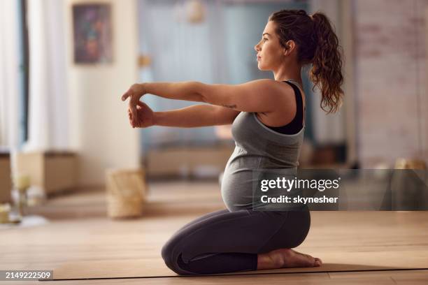 carefree pregnant woman stretching her arm at yoga studio. - zwanger stockfoto's en -beelden
