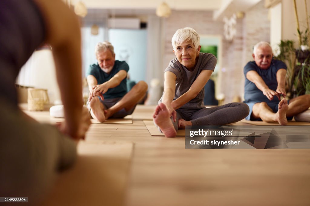 Aktive Senioren dehnen sich auf einem Fitnesskurs in einem Fitnessstudio.