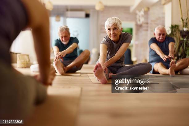 active seniors stretching on exercise class in a health club. - idoso imagens e fotografias de stock
