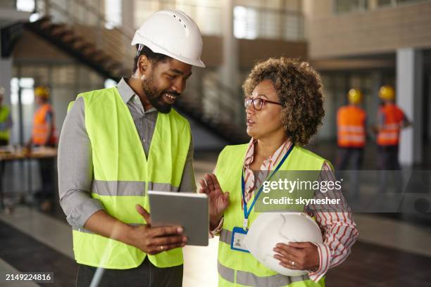 civil engineers talking while working on touchpad at construction site. - real estate developer stock pictures, royalty-free photos & images
