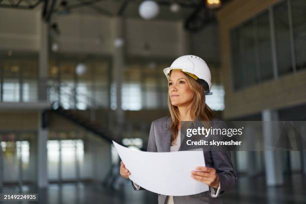 nachdenklicher innenarchitekt, der an plänen im gebäude arbeitet. - projektmanagement stock-fotos und bilder