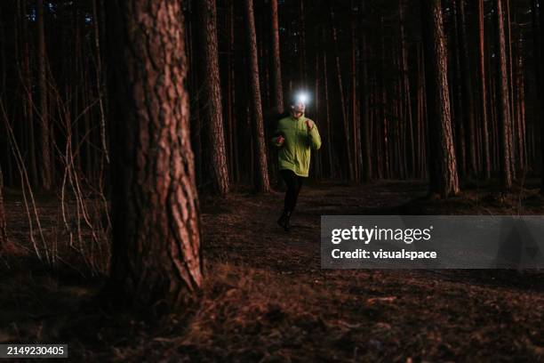 young woman navigates the trails of the forest on her evening run at dusk - head torch stock pictures, royalty-free photos & images