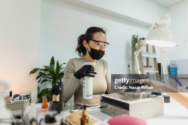 precautionary measures: manicurist sprays disinfectant on client's hands before service - hand sanitiser stock pictures, royalty-free photos & images