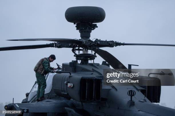 Pilot prepares an Apache helicopter as a fleet of more than a dozen Apache, Wildcat and Chinook helicopters assemble to take-off together from...