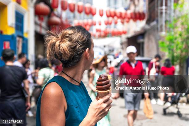 young woman holding a chocolate ice cream in kuala lumpur's chinatown. - sorvete chocolate chip - fotografias e filmes do acervo