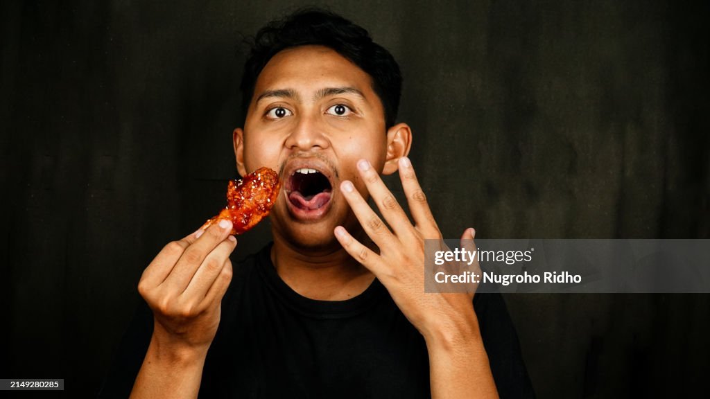 Young Male with Spicy Face Expression While Eating Spicy Fried Chicken