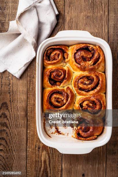 baked cinnamon rolls with apples in baking dish on rustic wooden table - cake tin stock pictures, royalty-free photos & images