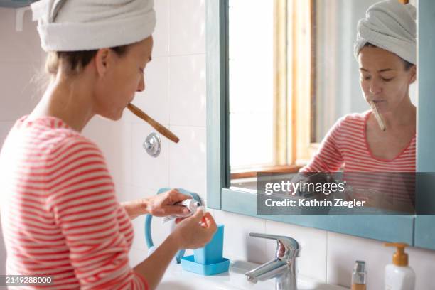 woman brushing her teeth in front of bathroom mirror - no make up stock pictures, royalty-free photos & images