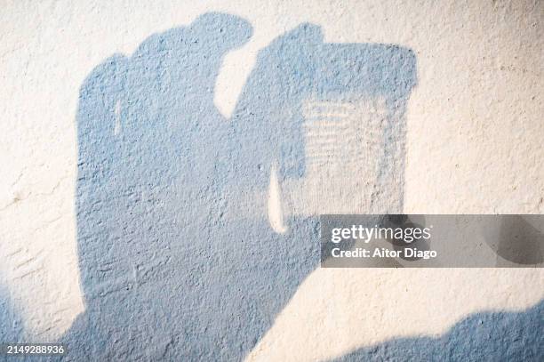 shadow of someone holding in the hand a container to collect urine samples for laboratory analysis. - urine stockfoto's en -beelden