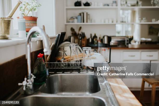 a pile of clean dishes sit on a draining board in a kitchen - küchenarbeitsplatte stock-fotos und bilder