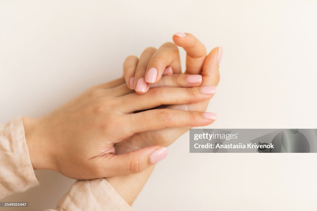 Manicure on female hands with light pink nail polish.