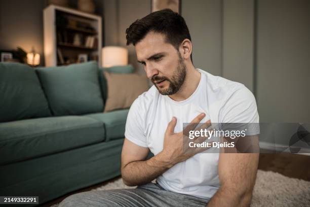 mid adult man having heartache at home. - heart disease stock pictures, royalty-free photos & images