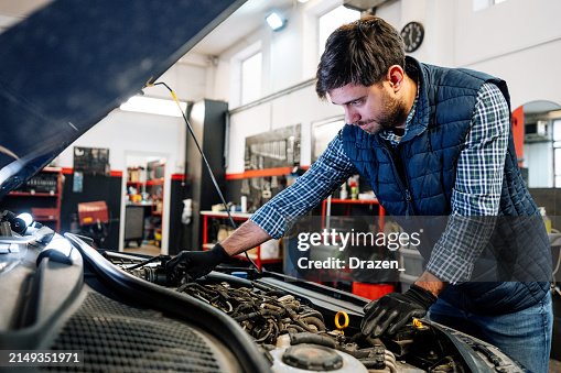 Car mechanic in workshop, checking engine andd using technologies Car mechanic in workshop, checking engine andd using technologies