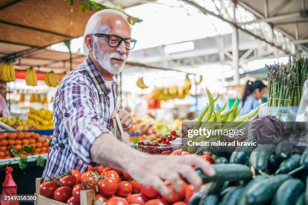 an elderly man sells organic vegetables at the market. - farmers market stock pictures, royalty-free photos & images