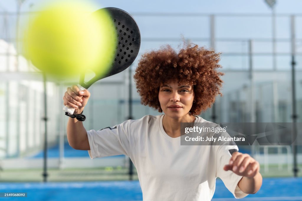 Afro woman playing paddle tennis in court