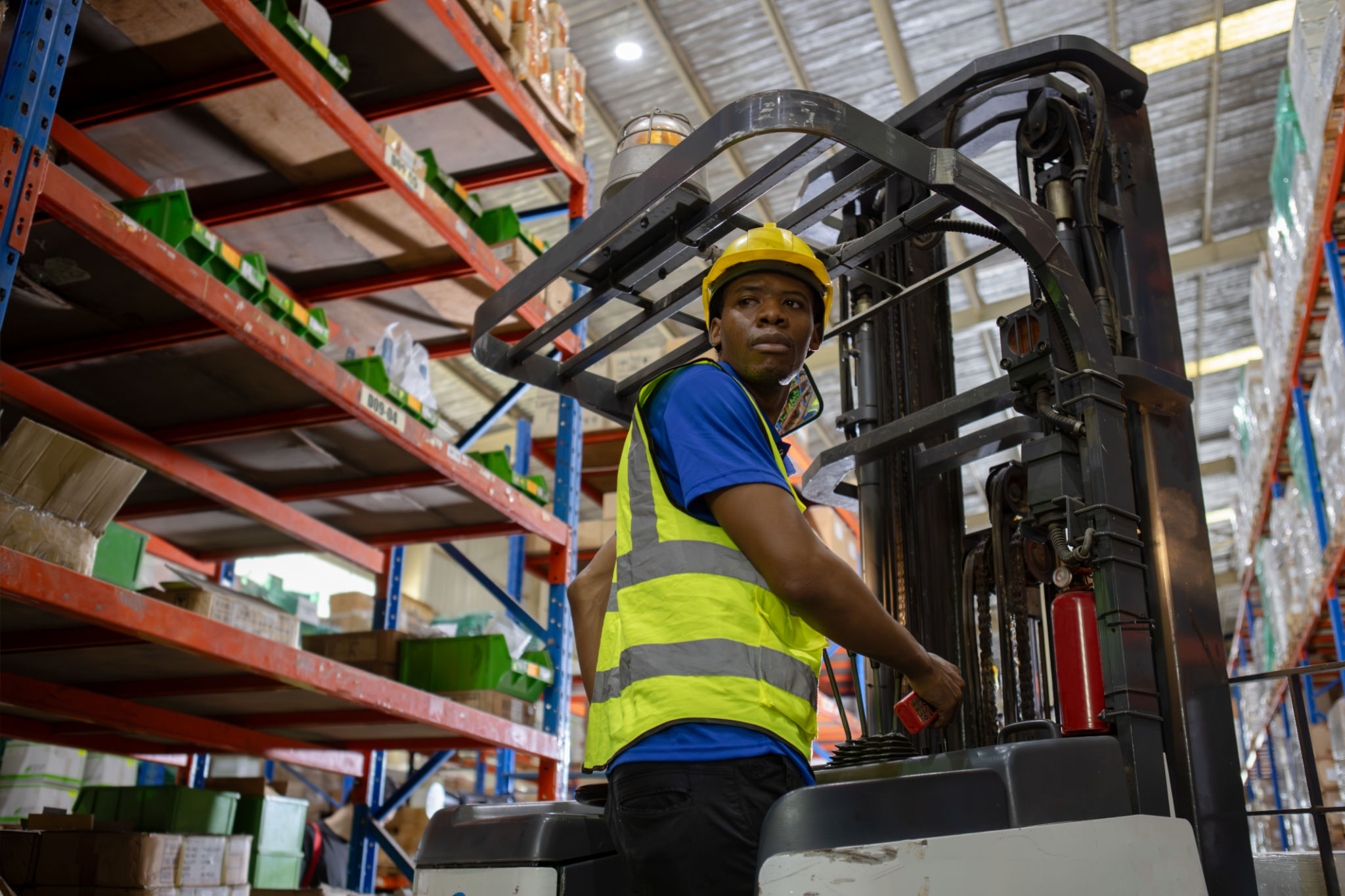 Man african american wear safety helmet driver forklift warehouse in factory. Male worker industrial operate. control loading container box. logistics export import concept. Man african american wear safety helmet driver forklift warehouse in factory. Male worker industrial operate. control loading container box. logistics export import concept.