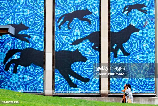 People are walking past a mural on the side of the Peel Art Gallery Museum and Archives building in downtown Brampton, Ontario, on April 23, 2024.