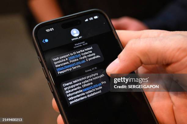 Man shows two messages on his mobile phone reading as 'Your passport and ID card are ready' and 'Issuance of documents suspended due to technical...