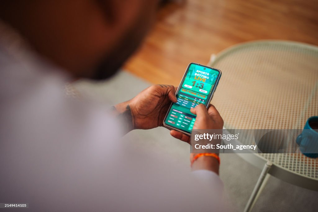 Indian man gambling online on a football match using his cell phone