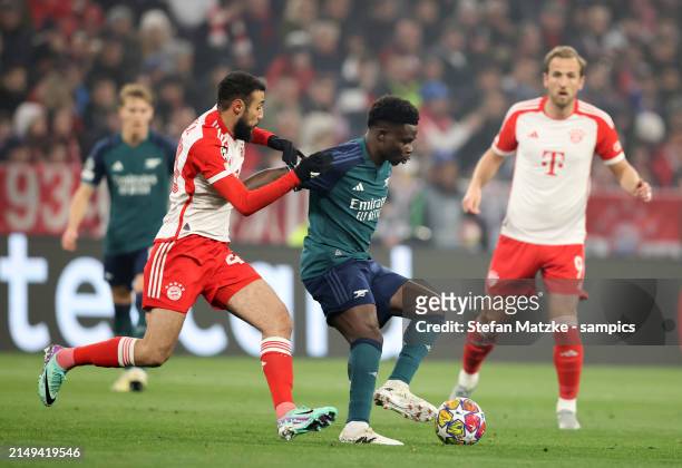 Noussair Mazraoui of FC Bayern Muenchen vies with Bukayo Saka of FC Arsenal during the UEFA Champions League quarter-final second leg match between...