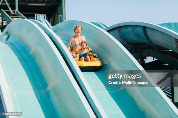 mother and daughter enjoys waterpark slide - water park stock pictures, royalty-free photos & images