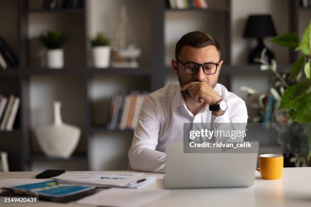 el hombre mira la pantalla de la computadora portátil se siente confundido al experimentar problemas - spyware fotografías e imágenes de stock