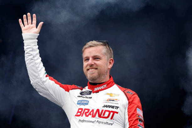 Justin Allgaier, driver of the BRANDT Chevrolet, waves to fans as he walks onstage during driver intros prior to the NASCAR Xfinity Series Ag-Pro 300...