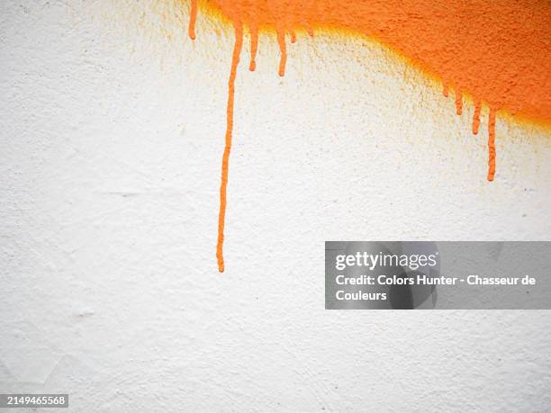 orange paint with drips on a textured white wall. sunlight. natural colors.paris, france. - graffiti stockfoto's en -beelden