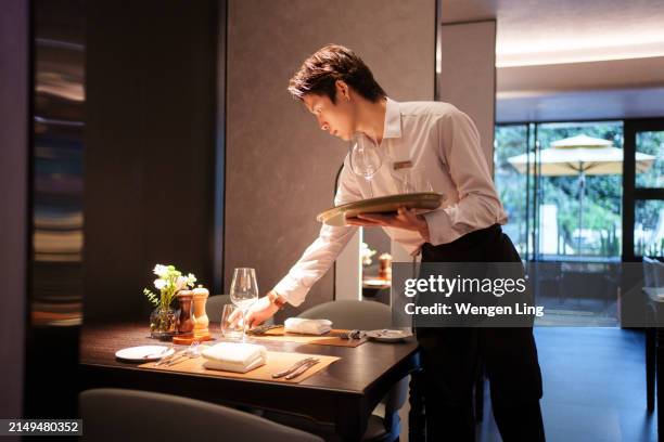 mann, der geschirr platziert - gastronomiebetrieb stock-fotos und bilder