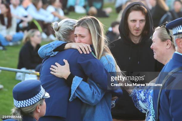 Police officer Amy Scott embraces a member of the public as she arrives for a community candlelight vigil for the victims of the Bondi Junction...