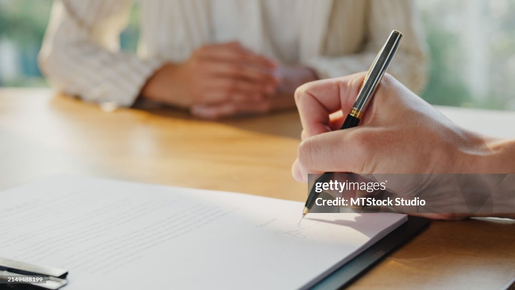 Primer plano de un joven empresario asiático firma un contrato de acuerdo de documento profesional de inversión en la oficina. Empresarios en el lugar de trabajo.