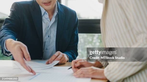 closeup of young asian businessman mentor corporate leader manager counselor communicate with businesswoman teaching interns staff engaged in discussion at office. businesspeople in workplace. - presentación comercial fotografías e imágenes de stock