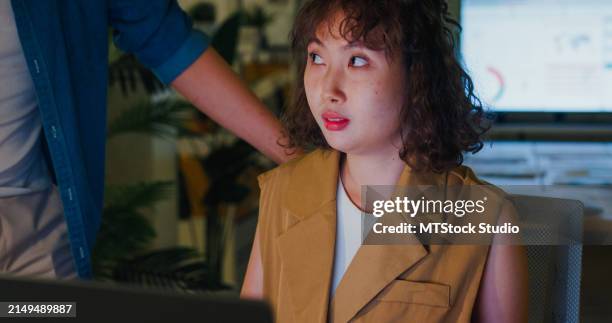 asian male manager accusingly expressing displeasure to young female employee suggesting a tense workplace situation in office at night. esg sustainable business office. - irritation stock pictures, royalty-free photos & images