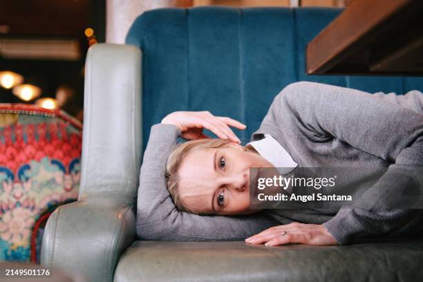 woman with hands over face lying on a couch, looking distressed. - verguenza fotografías e imágenes de stock