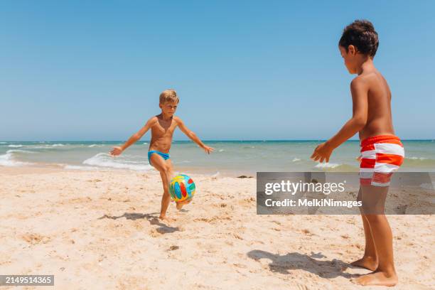 two boys playing football on the beach - kicking sand stock pictures, royalty-free photos & images
